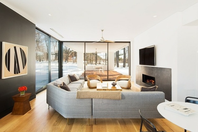 Drevená podlaha, sivá sedacia súprava, krb, čierne nástenné obrazové sklo sedací krbový krb čierna stena obrázok sklenená fasáda