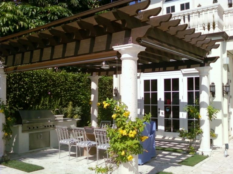 Romantická pergola v hnedej farbe s jedálenským kútom a grilom pergola v záhrade stĺpy z hnedého dreva terasa gril