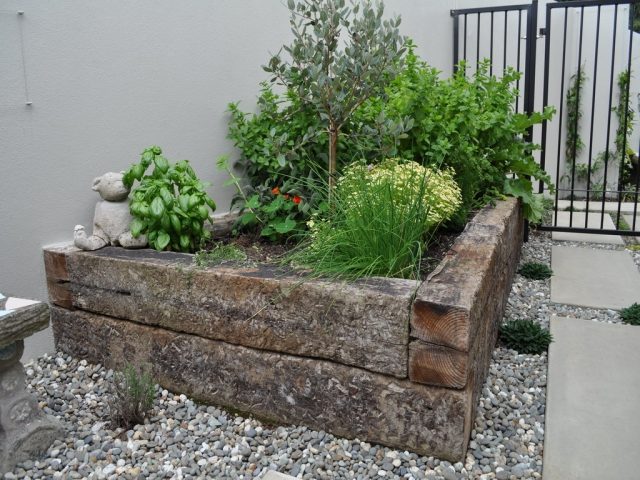 malá záhradná myšlienka rohový drevený trám vyvýšený s bazalkou