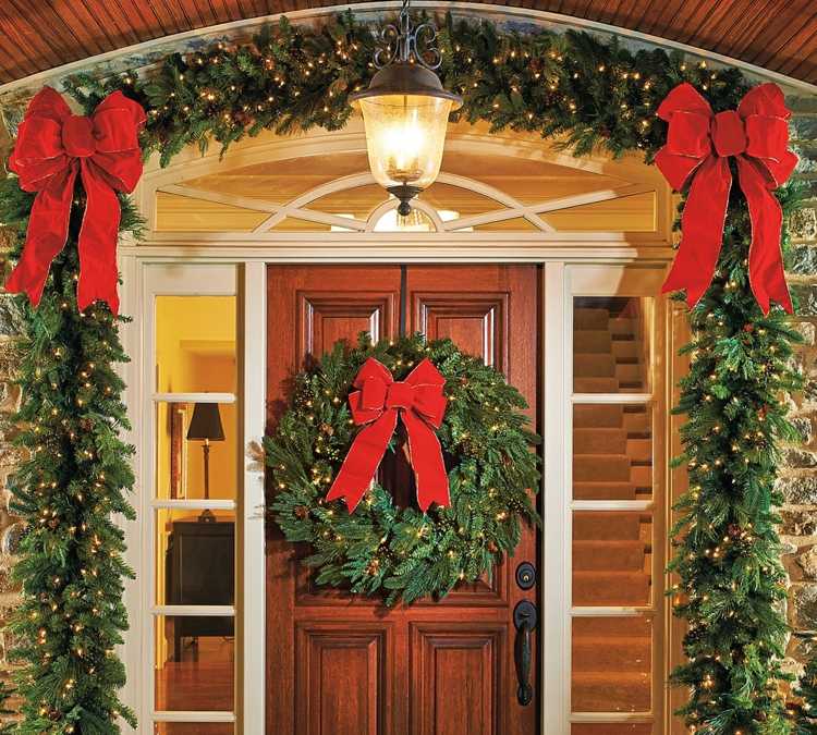 vianočná dekorácia s jedľovými girlandami rozprávkové svetlá lampa s červenou stužkou