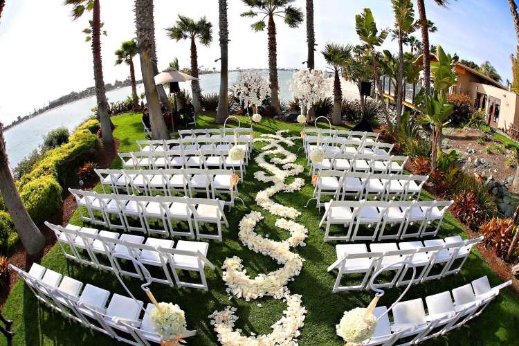 biele skladacie stoličky pre hostí a biele okvetné lístky ruží pozdĺž uličky svadba-manzelstvo-bez-weisse-ruzove-listy-ulicka