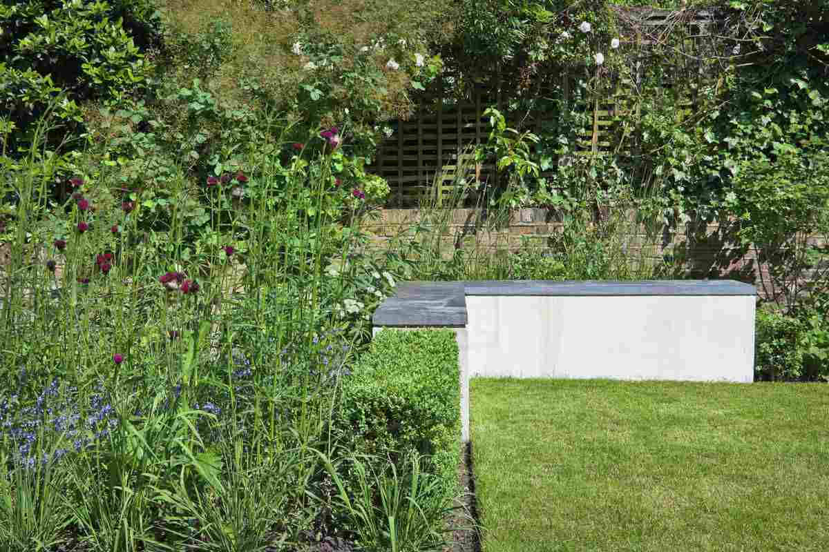 Jednoduchá rohová lavica so sedadlom z betónu a záhonmi v chatovom štýle