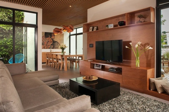 Rohová sedačka s čalúnením v hnedých tónoch v obývacej časti svetlo béžová farba s čalúneným nábytkom a drevenou stenou