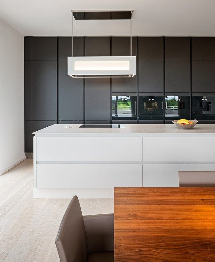kuchynský blok s integrovaným úložným priestorom a zariadením-matný čiernobiely kuchynský ostrovček puristický Penthouse-byt-kuchyňa-blok-integrované-zariadenia-skrytý-úložný-priestor-drevený stôl