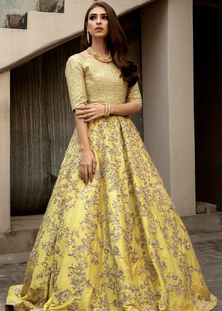 Pastelovo žlté šaty a honosne zdobená sukňa so striebornou výšivkou