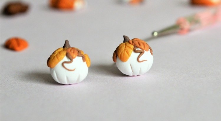 Malé biele tekvice vyrobené z remeselnej hliny, ozdobené listami v jesenných farbách