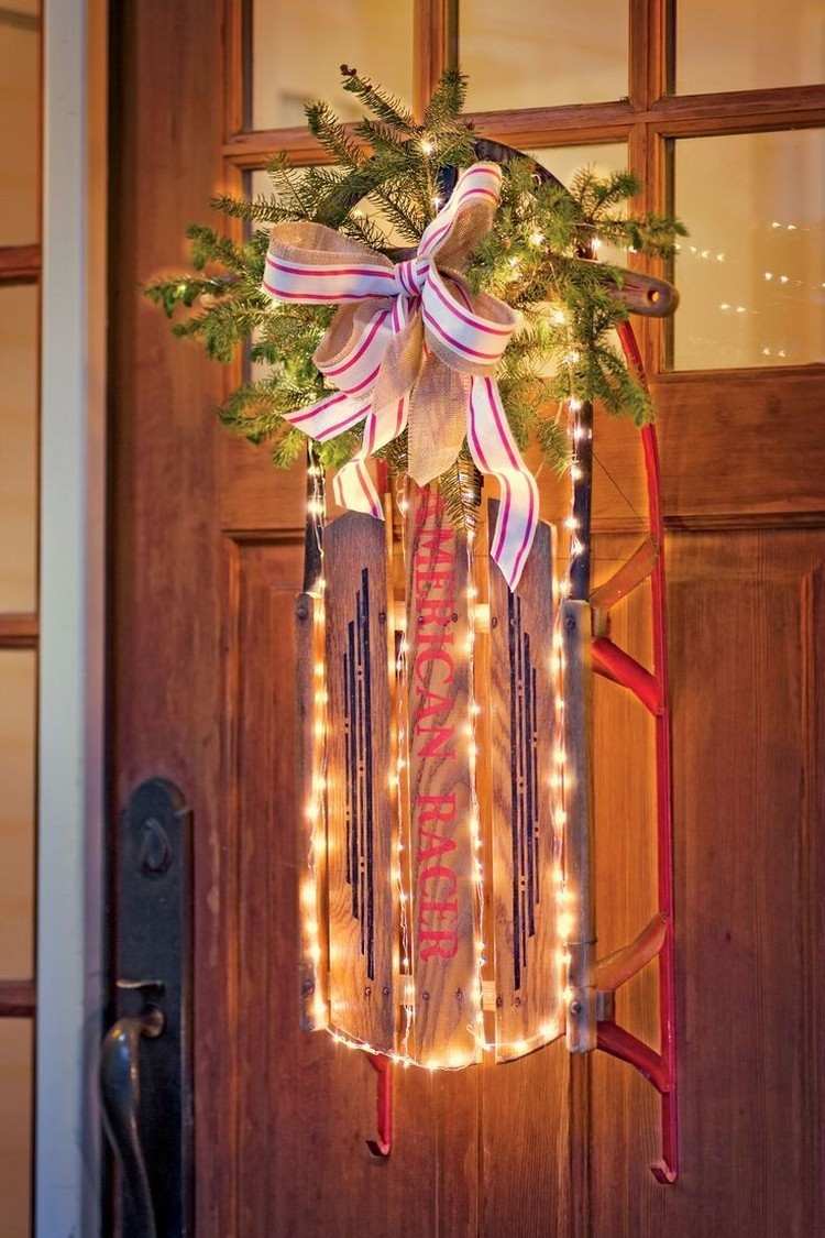 Na vchodových dverách viseli sánky osvetlené rozprávkovými svetlami adventná dekorácia-urob si sám-vonku-predné dvere-sánky-rozprávkové svetlá-jedľové ratolesti