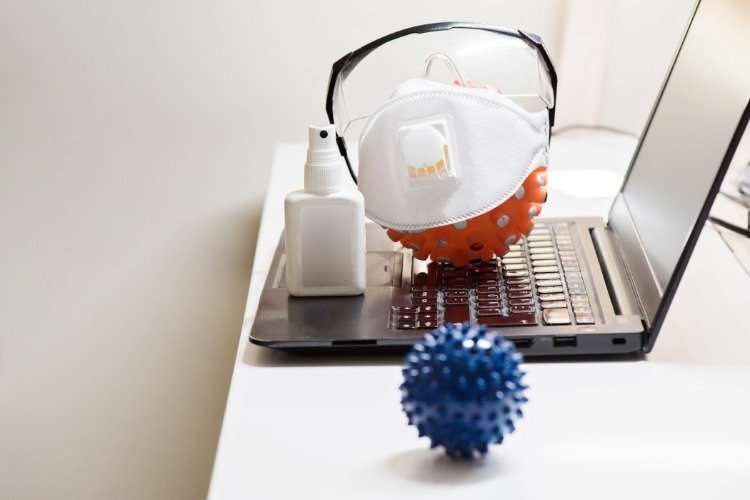 chrániče zubov a antiseptiká na laptome s ochrannými filmami podobnými koronavírusom
