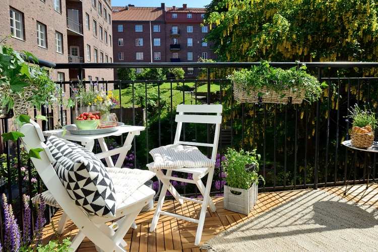 balkón mestského bytu potrebuje praktické a funkčné riešenia balkón-obklady-drevené skladacie-stoličky-bielo-kovové zábradlie-rastliny-kvety-kvetináče-mesto
