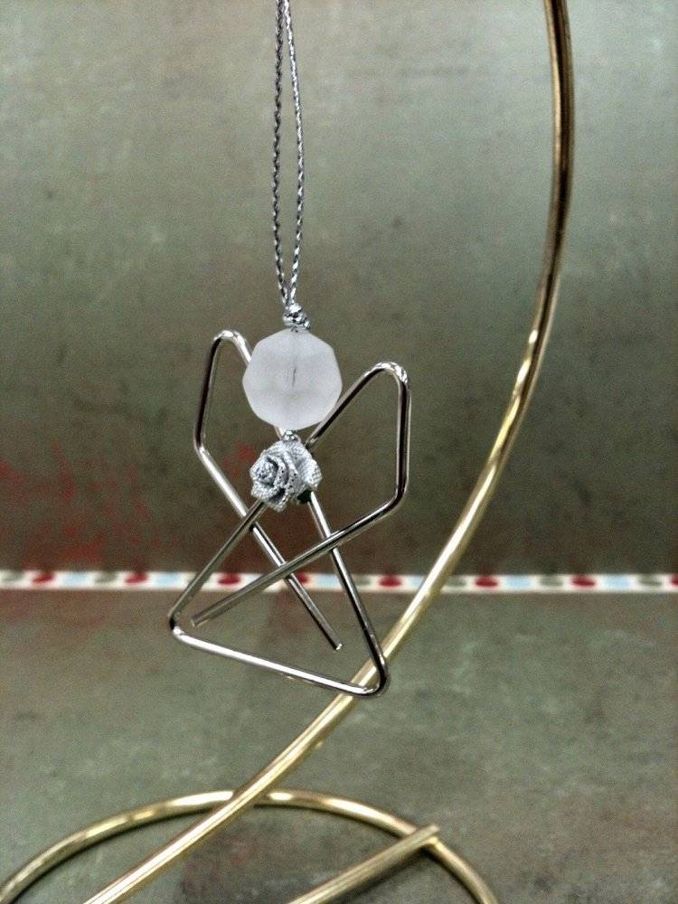 Anjeli strážni z kancelárskych sponiek ohýbajú strieborné prívesky vianočného stromčeka