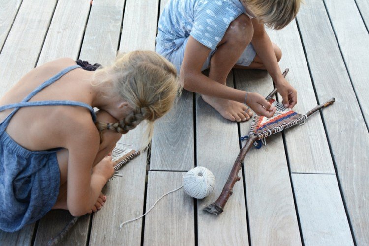 deti tkajú vlnu paličkovými vetvičkami