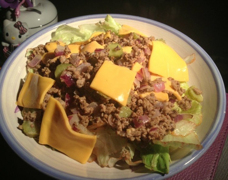 Šalát Big Mac preliaty plátkami taveného syra big-mac-šalát-jedlo-ľadový šalátové listy-cibuľa-mleté mäso-spracovaný syr-plátok-tanier