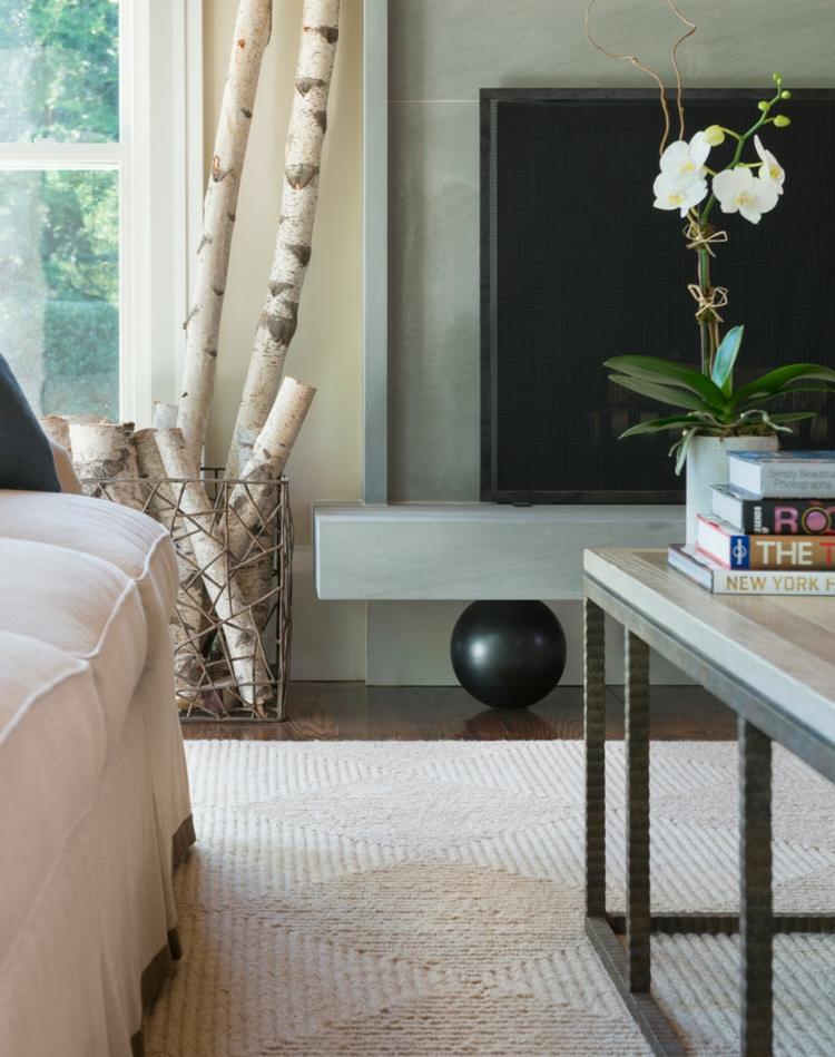 Kmeň brezy v koši vedľa krbu v obývačke brezový kmeň-dekorácia-vetvičky-košík-krb