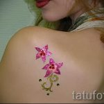 Татуировка с блясък с цветя на рамото на момичето - снимка