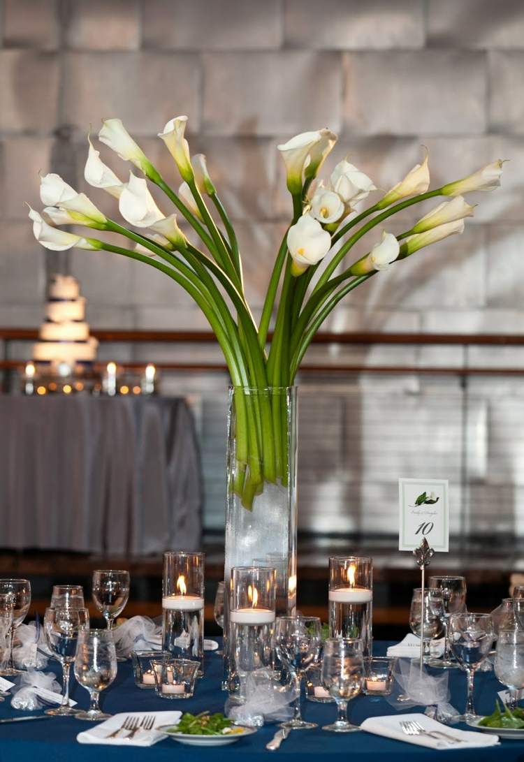 Dekorácia stola s bielymi kalami v sklenenej váze kvetinová dekorácia na svadobnú sklenenú vázu-callas-výzdoba stolu-plávajúce sviečky-obrúsok-príbor-číslo stolu