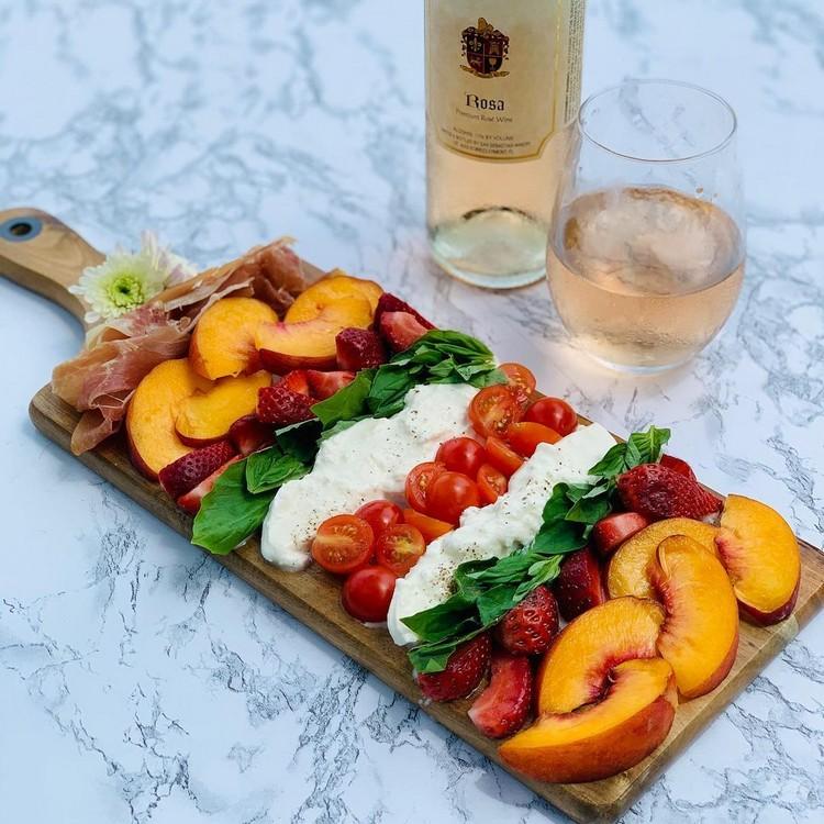 Svačinkový tanier s ružovou burratou, paradajkami, letným ovocím a šunkou