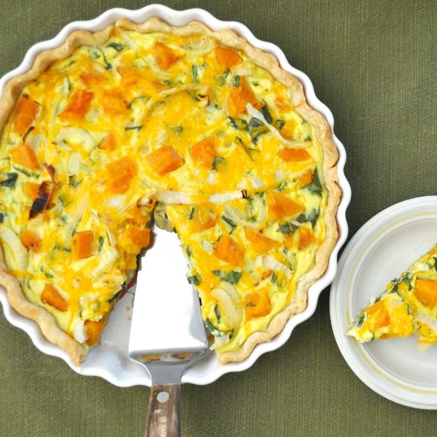 Lahodné maslové tekvicové quiche podávajte s cibuľou a tekvicou nakrájanou na kocky s kuchynskou špajdľou