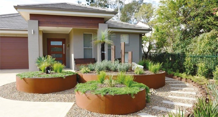 Okrúhle vyvýšené záhony v prednej záhrade so skalkou