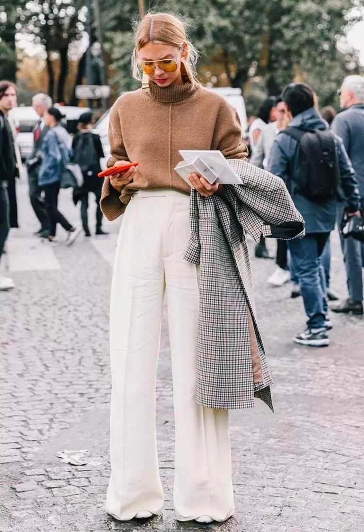 biele široké nohavice a hnedý sveter s károvaným kabátom