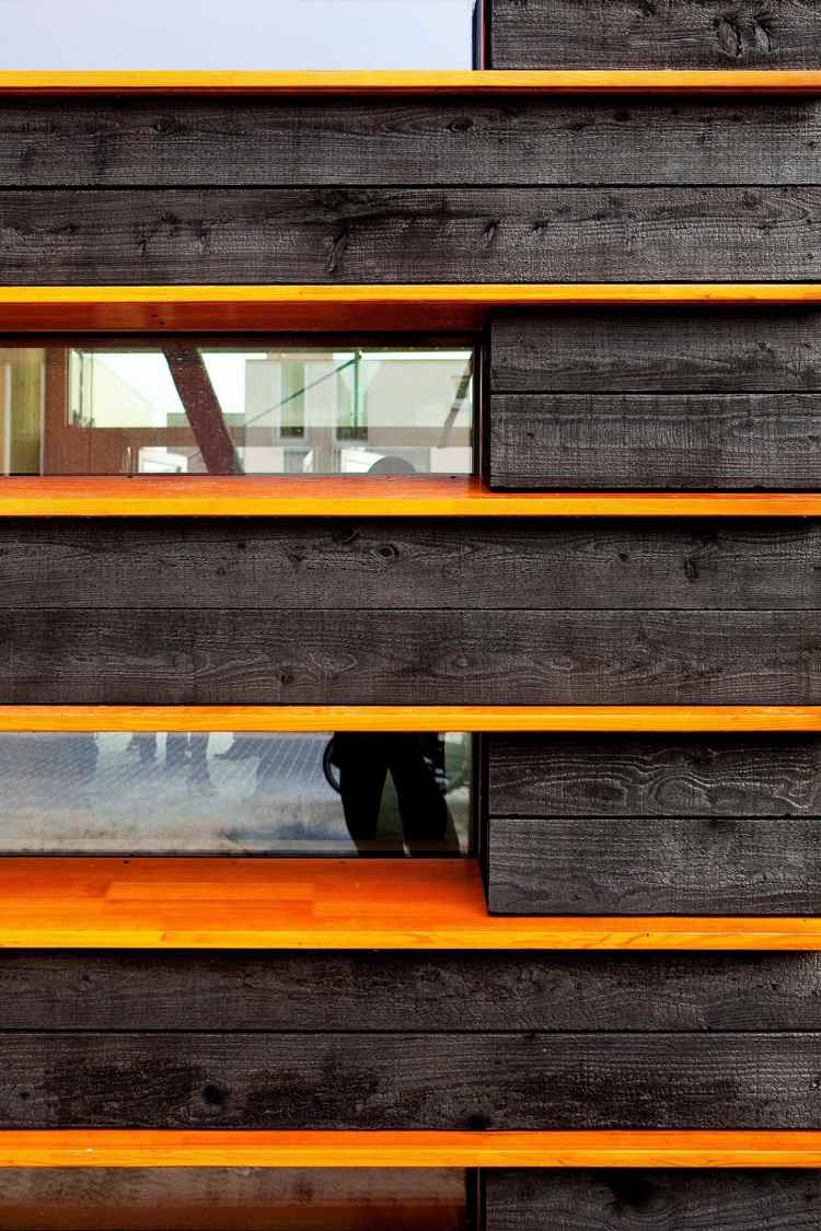 Fasádne zuhoľnatené drevo kontrastuje s oranžovým lakom
