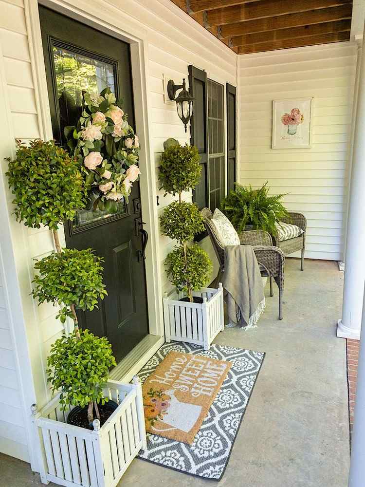 Dekoratívne stromčeky v kvetináčoch a dverový veniec ako letná dekorácia pre vchod do domu