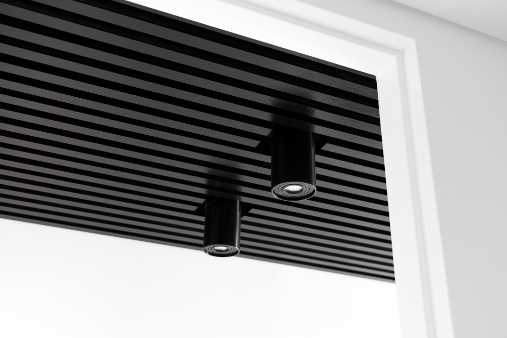 strop s čiernymi drevenými lamelami a moderným osvetlením s LED diódami
