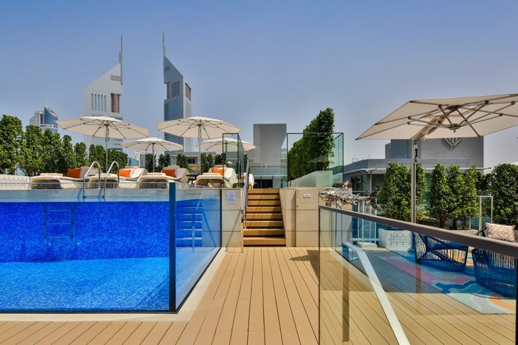 Sklenený bazén modrá mozaiková drevená terasa slnečníky strešná terasa