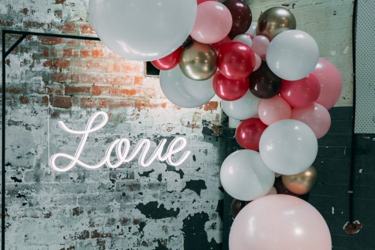 Stojan so závesným neónovým nápisom zo skla a ozdobou z balónov