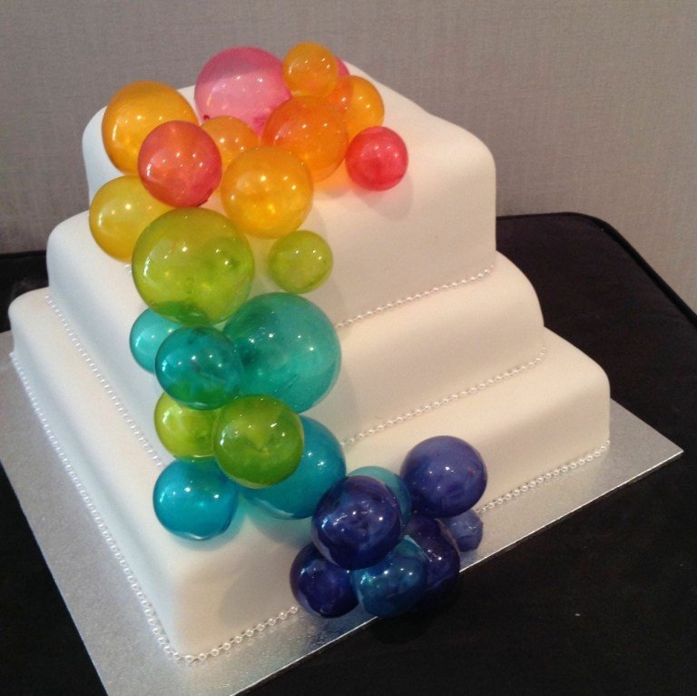 Priehľadné a farebné bubliny na bielej svadobnej torte pre optimistickú svadbu