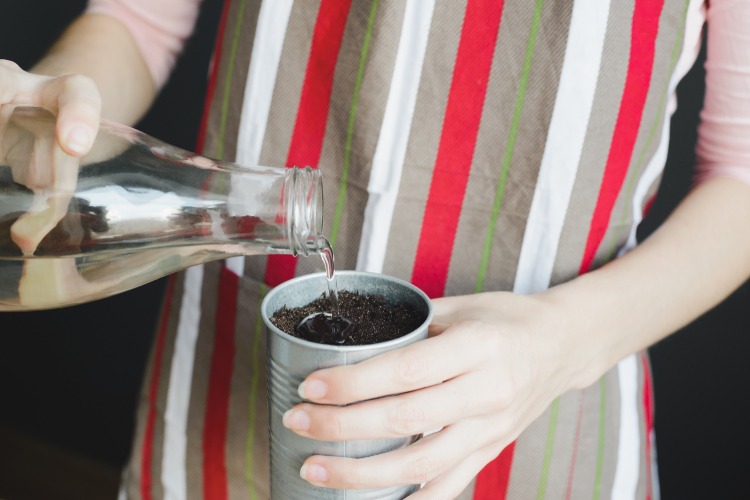 žena polievajúca pôdu v malom železnom hrnci