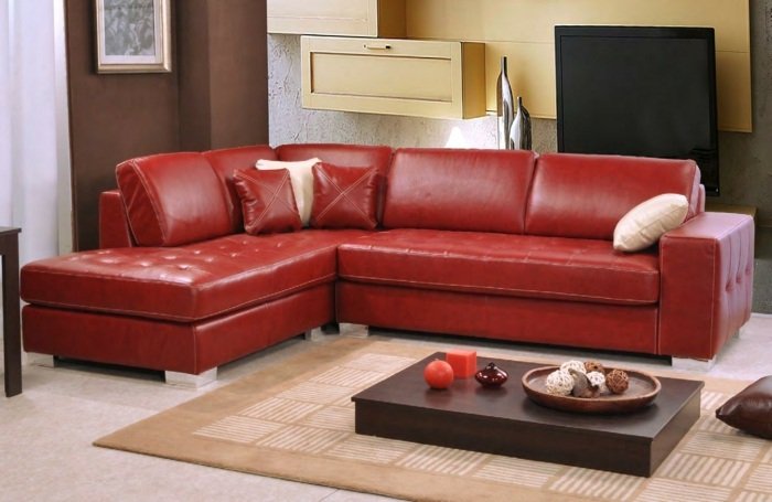 Rohový gauč vyrobený z červenej kože a hnedého dreveného stola