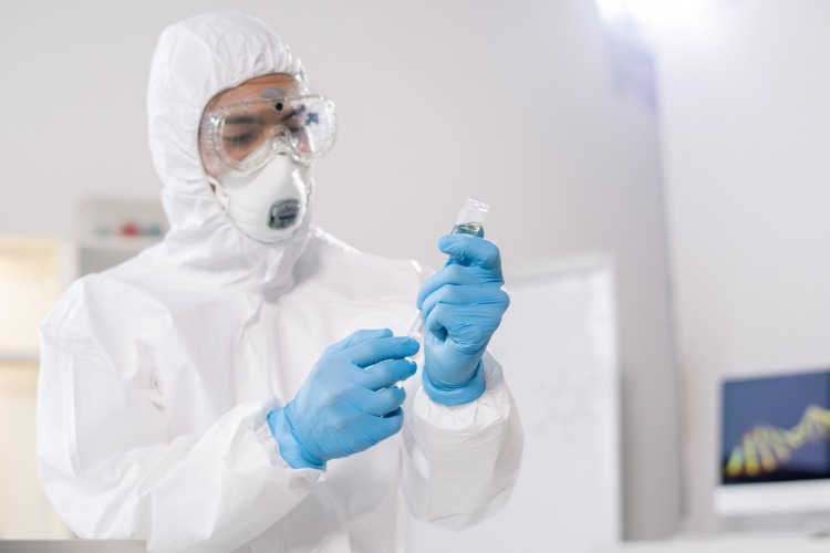 zdravotnícky pracovník v ochrannom odeve držiaci vakcínu proti koronavírusu