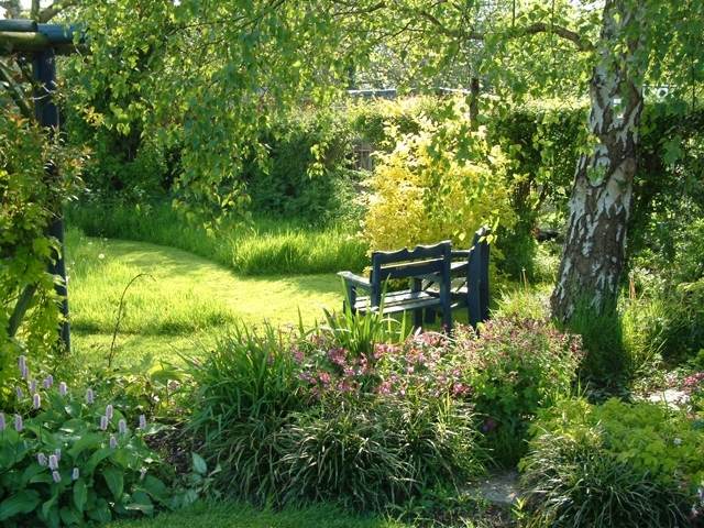 záhradná lavička v tieni krajinného dizajnu