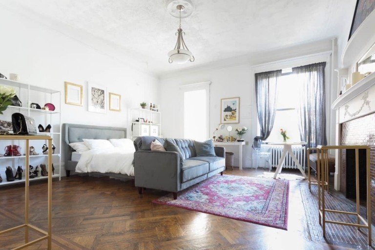 Obývacia izba a spálňa spoločne v podkrovnom apartmáne, v obývacích izbách je posteľ za pohovkou a Kilim a nástenná polica a stojan na topánky