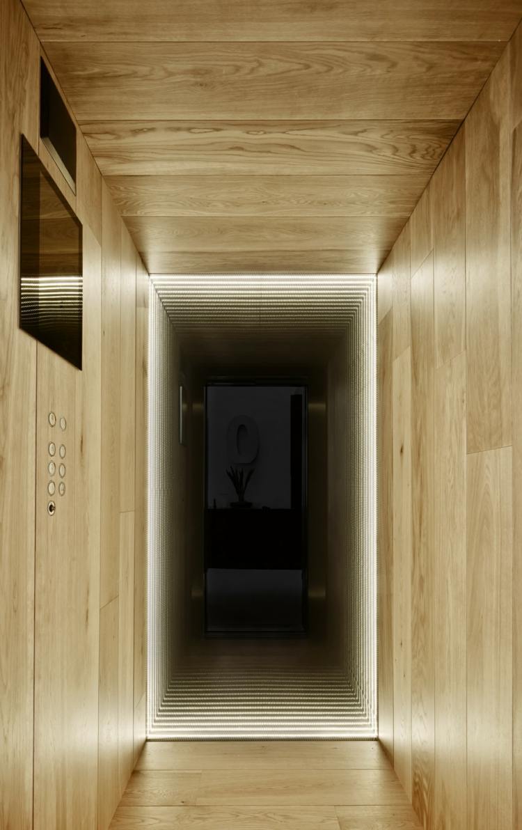 Pri zariaďovaní interiéru bolo použité dubové drevo Konopné lano-zábradlie-drevené obloženie-výťah-chodba-úzky-osvetlený-strop-steny-tlačidlá-obrazovka