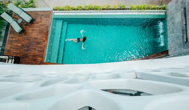 Vila s bazénom a drevenou terasou a sklenenými stenami a vodnými prvkami