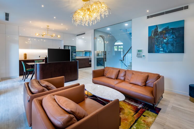 Vila vo Vietname obývacia izba s koženou sedačkou a kreslami a kuchyňou v bielej a čiernej farbe