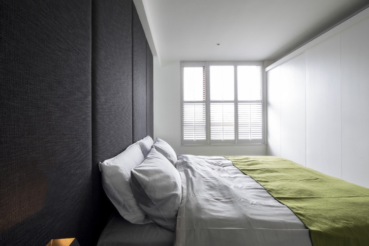 Čalúnená stena v sivej farbe slúži ako čelo postele v spálni farba-sivá-spálňa-posteľ-čelo-čalúnená-vstavaná skriňa-biela