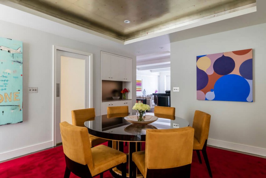 elegantný jedálenský stôl s čalúnenými stoličkami okrovej farby a farebnými obrázkami color-design-nápady-nyc-byt-jedáleň-koberec-červené-obrázky-moderné-umenie