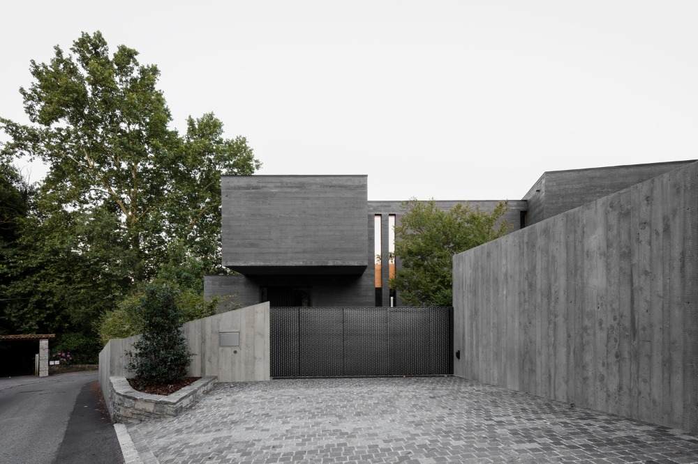 vchod do garáže v sivých tónoch a zadná časť betónového domu s úzkymi oknami