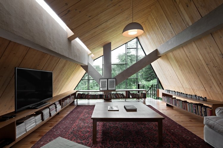 prázdninový dom z dreva lesné útočisko víkendový dom drevený obklad sklenená fasáda plochá obrazovka televízia drevený stôl zošikmená strecha kút na čítanie