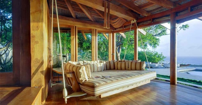 Terasa Opium Mustique má výhľad na čalúnenú drevenú podlahu Hojdačka na terase Opium Mustique s čalúnenou drevenou podlahou