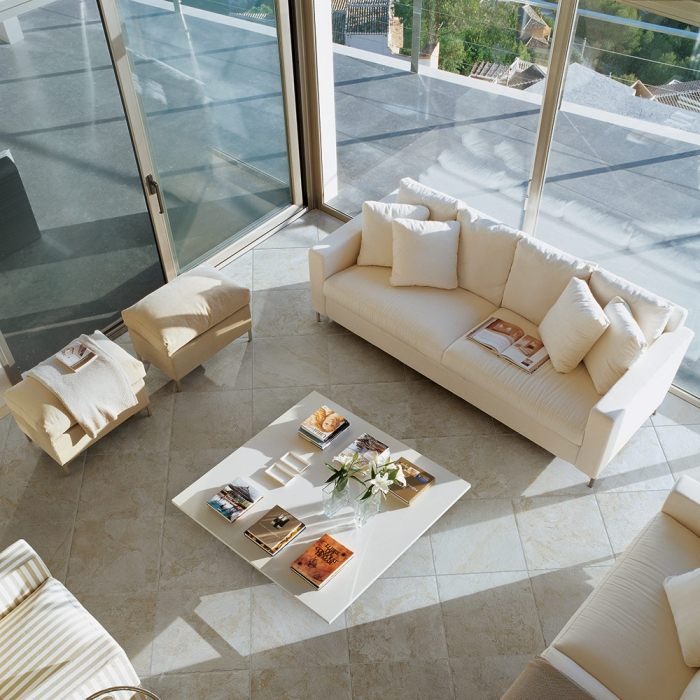 slnečná izba s krémovými pohovkami a podlahami v pieskovcovom vzhľade dlažba-pieskovec-vzhľad-podlaha-krémovo-farebné-sedacie súpravy-zasklenie od podlahy po strop