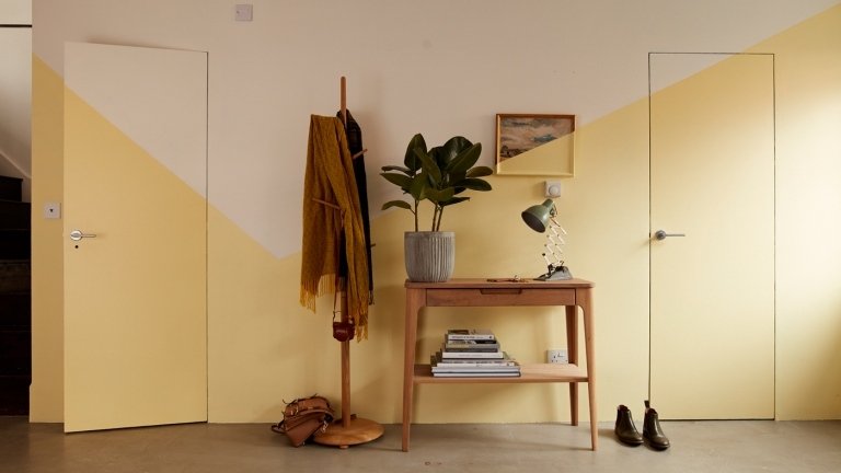 Vzor chodby natretý žltou a slonovinou pred dreveným stolom v ťavej farbe na chodbe