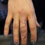 Готин пример за кръстосана татуировка, нанесена върху пръст - рисунката е подходяща за кръстосана татуировка на левия пръст