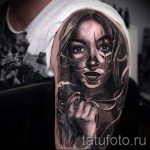 Fotó egy lány tetoválási portréjáról mintákkal az arcán és pisztolyával a kezében