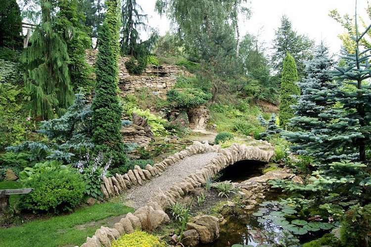 Svieža záhrada s niekoľkými záhradnými chodníkmi, jazierkom a zelenými rastlinami terénne úpravy-stráň-hrubý-vodný potok-most-ueppig-stromy