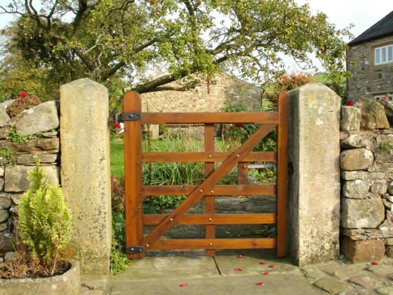 Záhradná brána z dreva v priehľadnom a rustikálnom prevedení záhradná brána vyrobená z dreva v rustikálnom vzhľade betónová kamenná stena