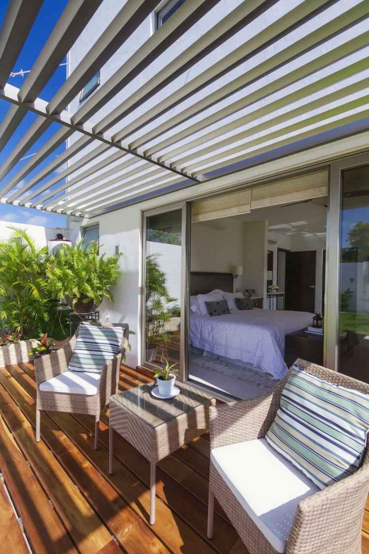 Hliníkové lamely poskytujú príjemný tieň materiály-zastrešenie terasy-záhradný nábytok-kreslo-plast-ratan-béžovo-sedací vankúš-drevená podlaha-dvere na terasu-spálňa