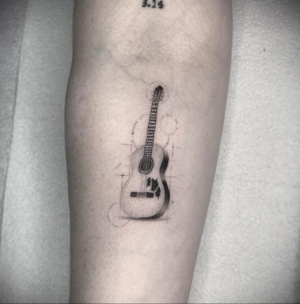 Tatuaż na gitarze klasycznej na zgięciu ramienia - zdjęcie